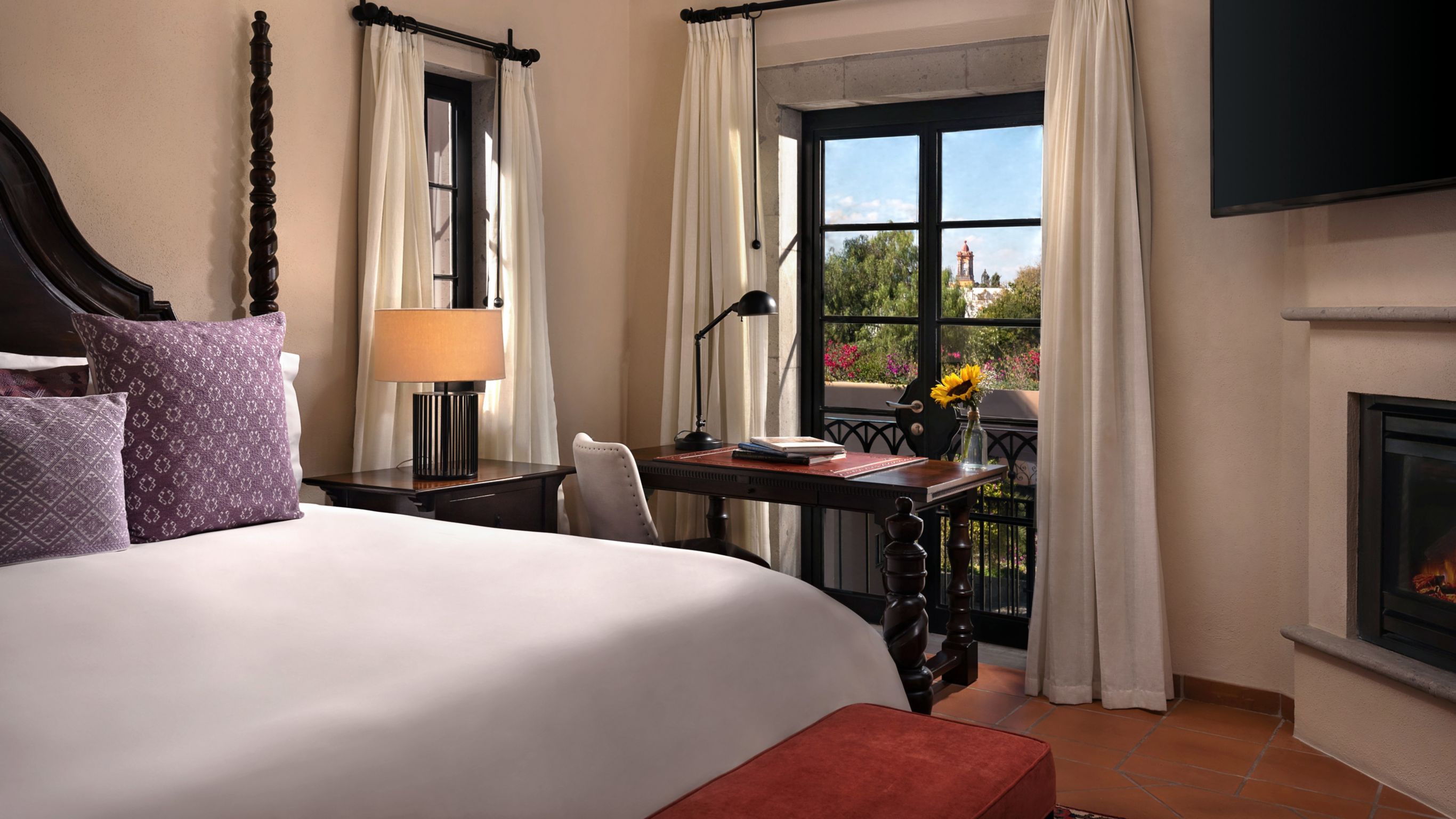 Elegant hotel room with two queen beds, warm lighting, and a balcony overlooking trees.